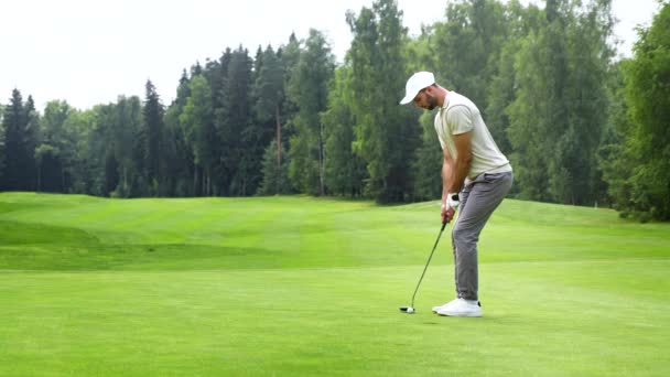 Jeune homme frappant une balle de golf avec un club de golf — Video