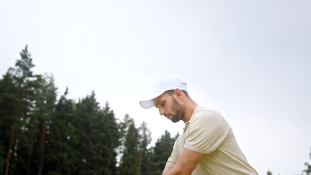 Jeune homme frappant une balle de golf avec un club de golf — Video