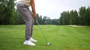 Üniformalı genç golfçü sopayla vurgun yapıyor.