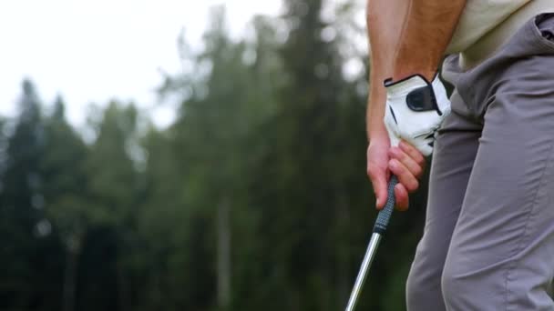 Händerna på en ung man som håller en golfklubba på planen — Stockvideo