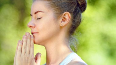 Yogada meditasyon yapan genç bir kadın namaste asana 'da el ele tutuşuyor.