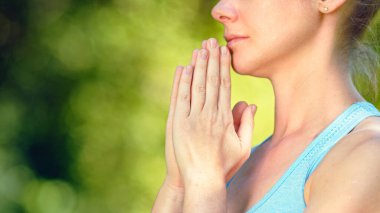 Mavi bluzlu genç kadın yoga uygulayıcısı rahatlamayla ilgili meditasyon yapıyor namaste asana el ele tutuşuyor.