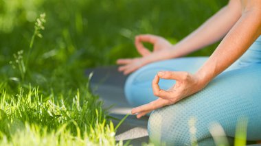 Mavi eşofmanlı genç bayan antrenör yoga yaparken Lotus 'un taytla el ele tutuşup poz vermesini sağlıyor.