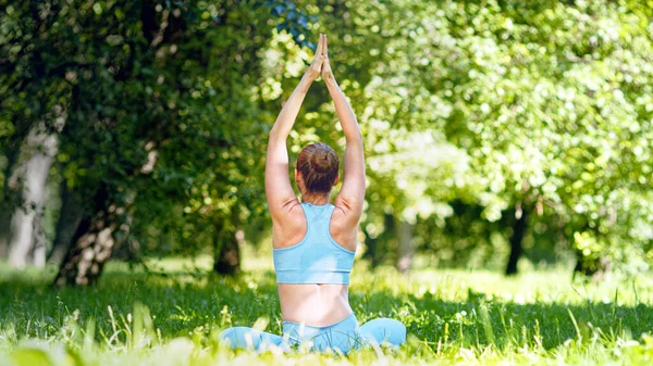 Blondýny dáma sportovec medituje sedí v jóga asana lotosu po cvičení na zeleném parku — Stock fotografie