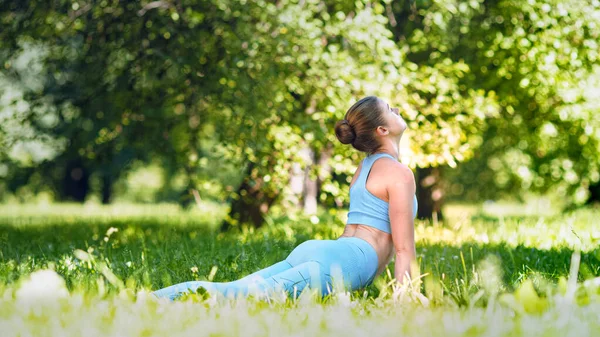 Professional athlete lady blonde in blue tracksuit performs yoga exercise — Stock Photo, Image