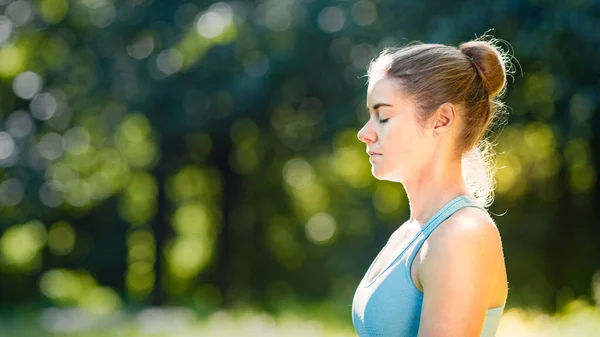 Young woman athlete in blue top relaxes after exercises and meditates breathing deeply — Stock Photo, Image