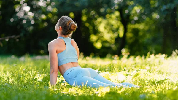 Blonde young woman yoga trainer in blue tracksuit changes upward facing dog pose exercising — Stock Photo, Image