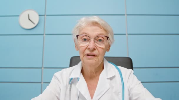 Överläkare konsulterar patienten på videocall på kliniken — Stockvideo