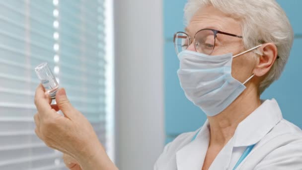 Femme médecin avec masque remplit seringue avec vaccin à l'hôpital — Video