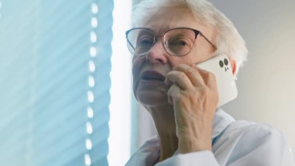 Fachärztin mit Brille telefoniert im Krankenhaus — Stockvideo