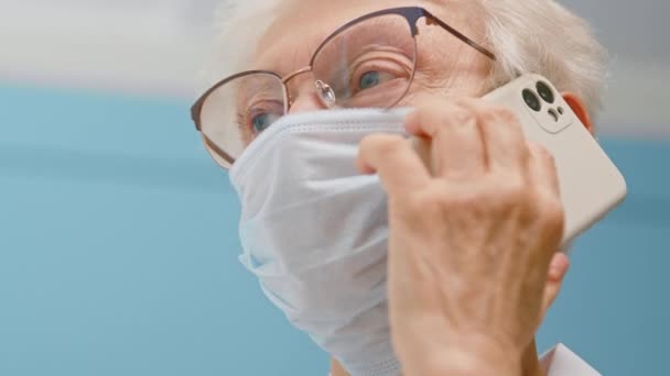 Médecin principal en masque parle au téléphone dans le bureau de l'hôpital — Video