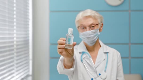 Ältere Ärztin steht in Klinik im Fokus mit Antiseptikum — Stockvideo