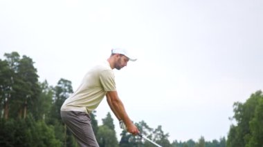 Genç sporcu dışarıda golf oynuyor.