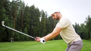 Golf sahasında golf oynayan genç bir golfçü.