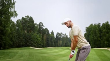Dışarıda golf oynayan üniformalı genç bir adam.