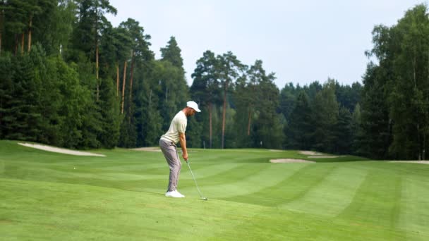 Hombre joven en uniforme jugando al golf en el césped — Vídeos de Stock