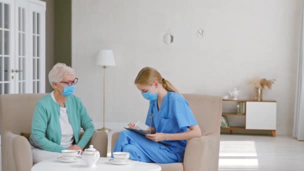 Gammal kvinnlig patient med medicinsk mask och läkare i rummet — Stockvideo