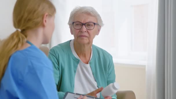 Vecchia paziente donna tiene bottiglia pillola annuendo testa al medico — Video Stock