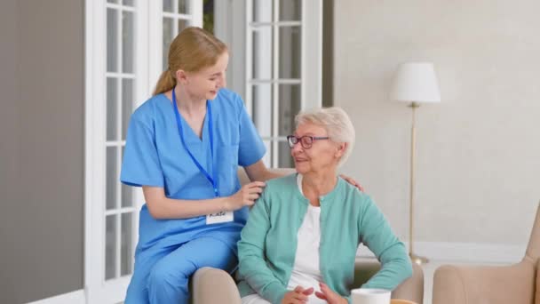 Glimlachende verpleegster zorgt voor oudere vrouw in geassisteerd wonen — Stockvideo