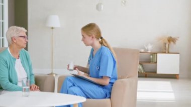 Doktor klinikteki yaşlı hastaya bir şişe vitamin veriyor.