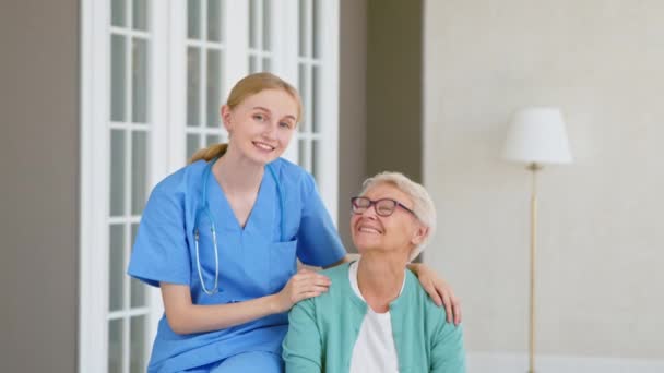 Dokter met stethoscoop knuffels senior vrouw poseren in kamer — Stockvideo