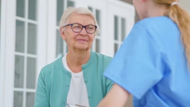 Felice signora anziana annuisce testa ascoltando caregiver in ufficio — Video Stock