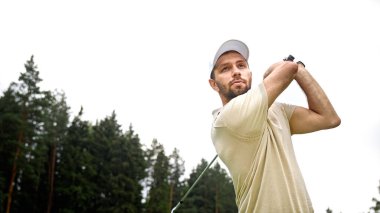 Genç bir erkek sahada golf oynuyor.