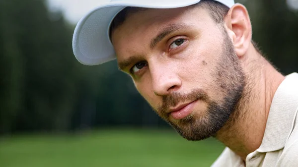 Portrait of a young man in a cap playing golf on the field