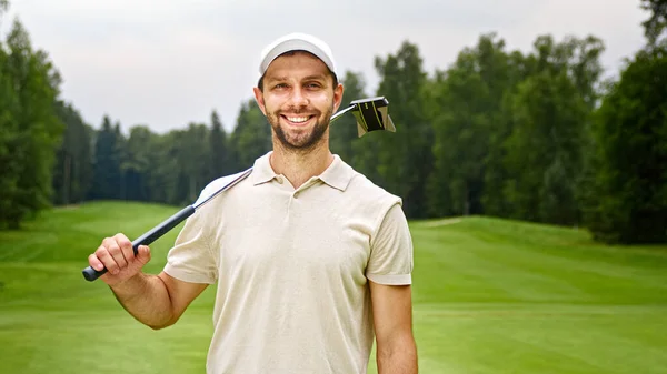 Hombre Joven Con Club Golf Mirando Cámara Campo Golf Aire —  Fotos de Stock