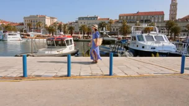 Une jeune fille en robe bleue marchant le long de la jetée dans la ville. Split, Croatie — Video