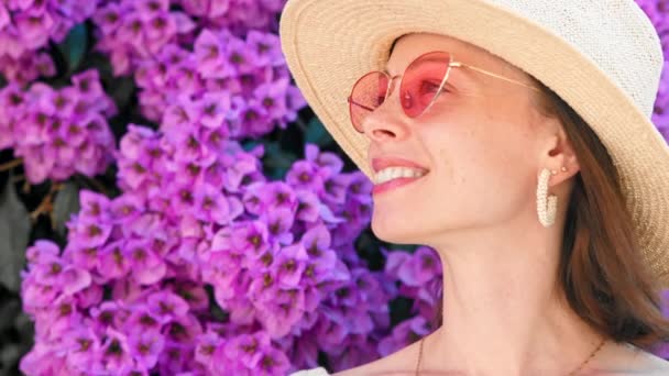 Sonriente chica en un sombrero en flores de color lila de cerca — Vídeos de Stock