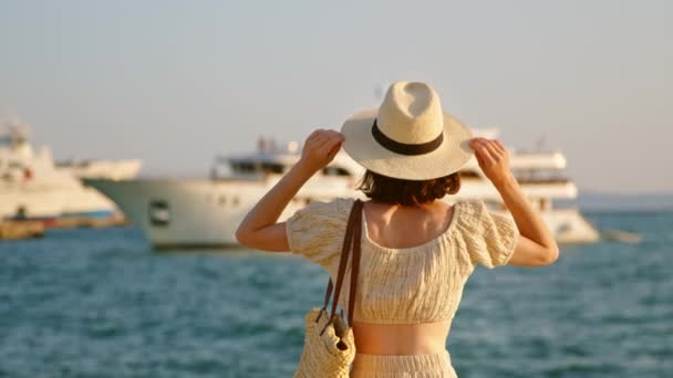 Молода жінка в капелюсі дивиться на море, відео 6k — стокове відео
