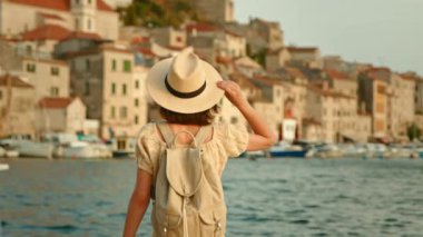 Şapkalı genç kız rıhtımdan denize bakıyor, yavaş çekim videosu.