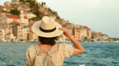 Rıhtımdan şehre bakan şapkalı çekici kız.