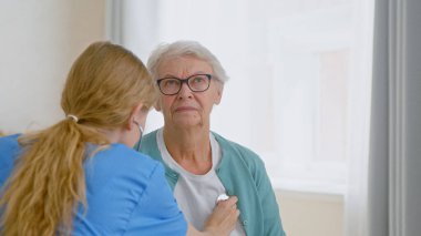 Yaşlı kadın hasta steteskopla muayene ediliyor ve doktor kalp atışlarını dinliyor.