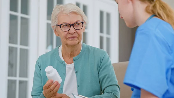 Seniorin mit Brille hält Pillen-Flasche im Zimmer — Stockfoto