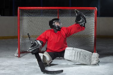 Young goalkeeper catching a puck clipart