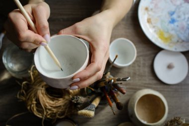 Seramik el yapımı bir kaseyi elle boyama işlemi. Sanatçının güzel kadın ellerine dikkat edin..