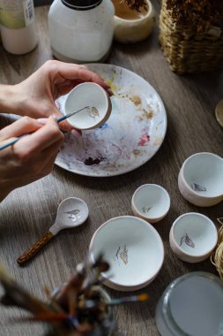 Seramik el yapımı bir kaseyi elle boyama işlemi. Sanatçının güzel kadın ellerine dikkat edin..