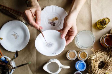 Elle boyama işlemi seramik bir el yapımı tabaklar yaptı. Seçici odak.