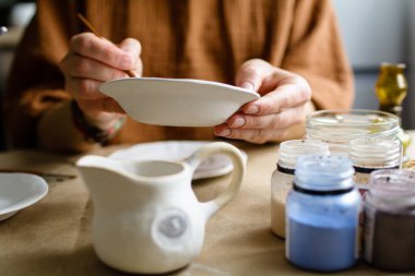 Elle boyama işlemi seramik bir el yapımı tabaklar yaptı. Seçici odak.