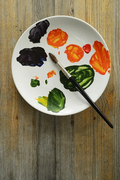Кисть и краски на тарелке — стоковое фото