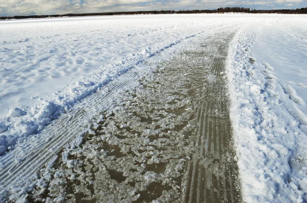 Estrada e trilhas em lago coberto de neve congelado — Fotografia de Stock