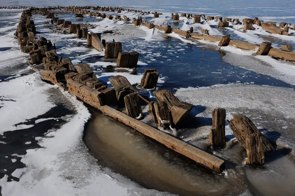 Resterna av en träbrygga på sjön på vintern — Stockfoto