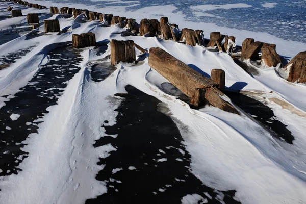 Остатки деревянного пирса во льду на озере — стоковое фото