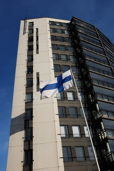 Ondeando la bandera nacional de Finlandia junto a un edificio moderno —  Fotos de Stock