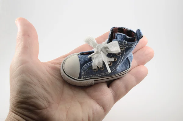 Tiny denim shoe on the palm — Stock Photo, Image