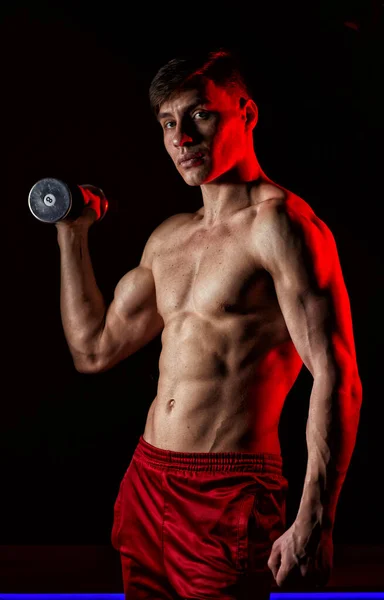 筋肉運動選手の男性は黒を背景に運動します 赤の背景光 — ストック写真