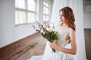 Güzel, yumuşak bir düğün buketi. Kremalı güller ve gelinin ellerinde östoma çiçekleri.