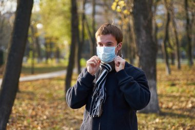 Sokakta yüzüne tıbbi maske takan ceketli bir adam.